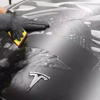 Applying XPEL Lakkbeskyttelse SGN BASE on a Tesla vehicle hood for protection.