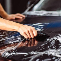 Applying XPEL Lakkbeskyttelse SGN BASE with a squeegee on a car hood.