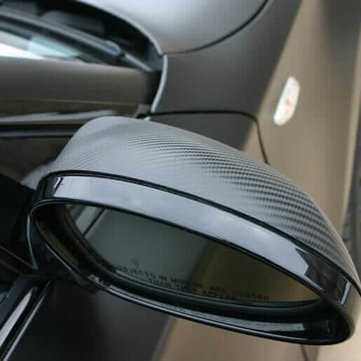 Carbon car wrapping detail on a car side mirror, showcasing premium carbon fiber texture.